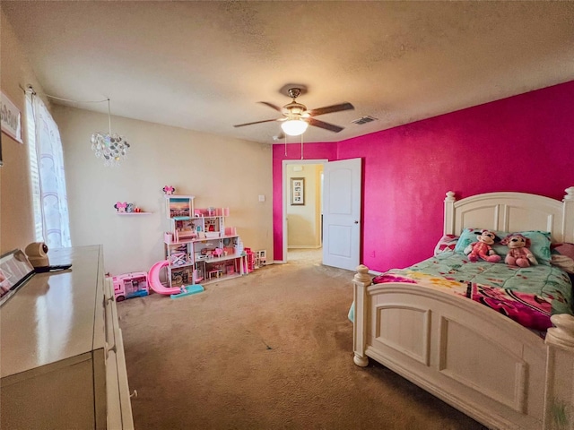 carpeted bedroom featuring ceiling fan, visible vents, and a textured ceiling