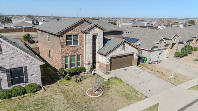 view of front of house with concrete driveway, stone siding, fence, and a residential view