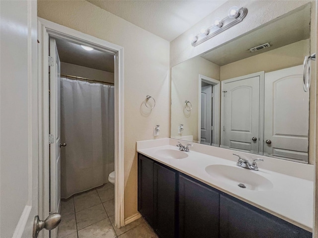 full bath featuring tile patterned floors, a sink, toilet, and double vanity