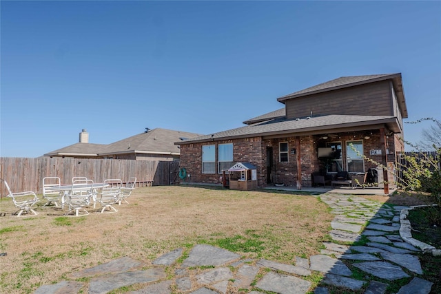 back of property with a yard, a patio area, brick siding, and a fenced backyard