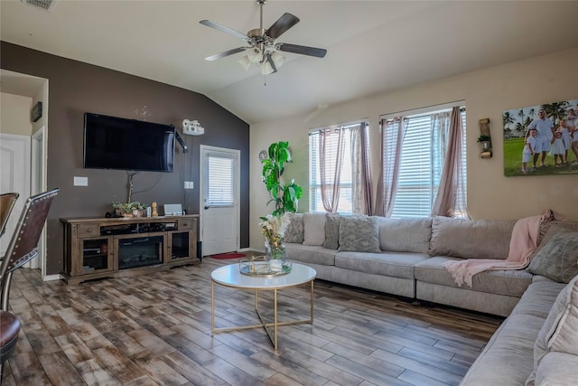 living area with lofted ceiling, visible vents, wood finished floors, and a ceiling fan