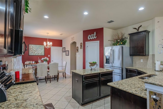 kitchen with arched walkways, light tile patterned floors, high end fridge, visible vents, and decorative backsplash