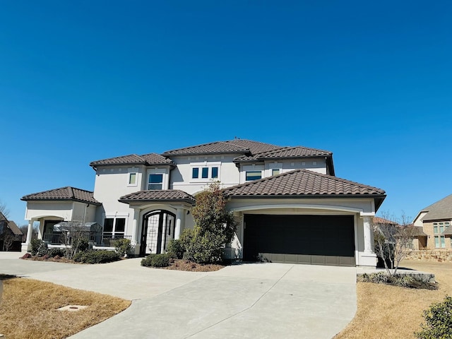 mediterranean / spanish house featuring a garage, concrete driveway, a tile roof, and stucco siding