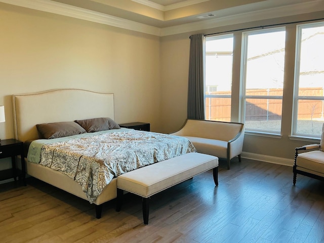 bedroom featuring baseboards, wood finished floors, visible vents, and crown molding