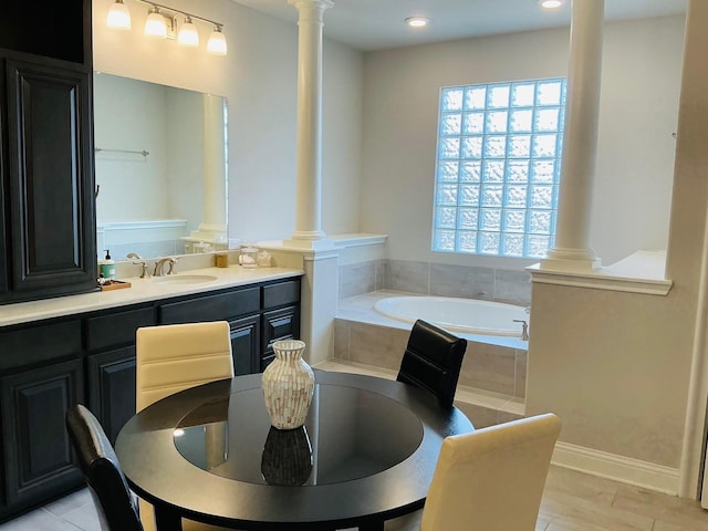 bathroom featuring a garden tub, vanity, and ornate columns