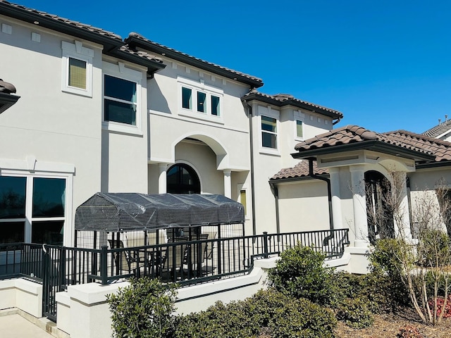 exterior space with a tile roof and stucco siding