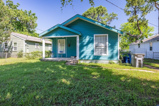 view of front of house with covered porch, a front lawn, and fence