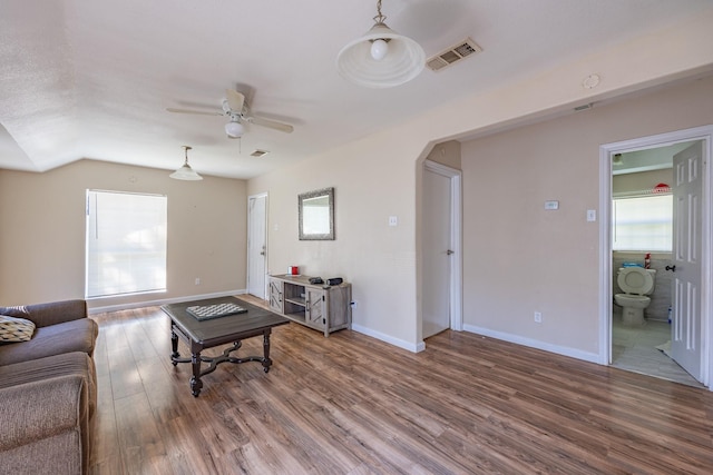 living area with arched walkways, visible vents, light wood-style flooring, and baseboards
