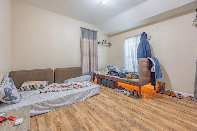 bedroom with vaulted ceiling and wood finished floors