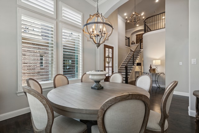 dining room featuring a chandelier, a high ceiling, dark wood-style flooring, baseboards, and stairs