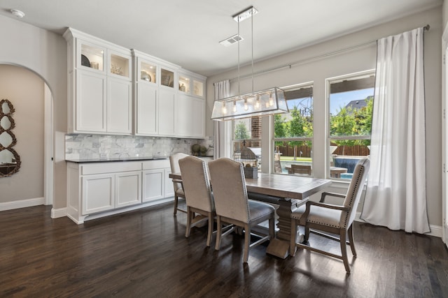 dining room with arched walkways, visible vents, dark wood finished floors, and baseboards