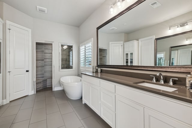 full bathroom with a freestanding tub, visible vents, a sink, and tile patterned floors