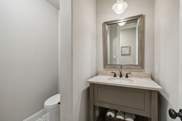 bathroom featuring toilet, vanity, and baseboards