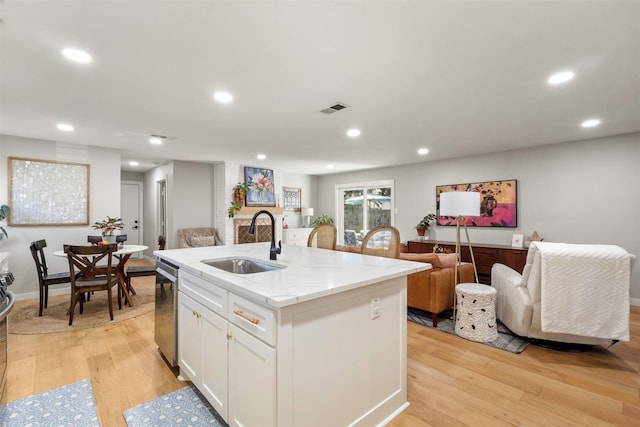 kitchen with light wood-style floors, a center island with sink, visible vents, and a sink