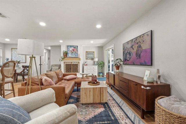 living area with a fireplace, visible vents, wood finished floors, and recessed lighting