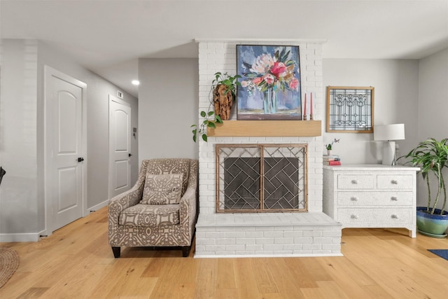 living area featuring a fireplace, wood finished floors, and baseboards