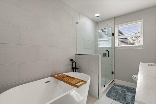 full bath featuring tile patterned flooring, a freestanding bath, a shower stall, and tile walls