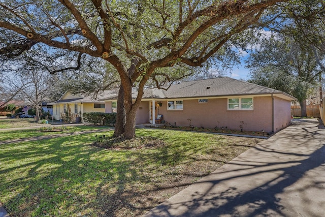 single story home featuring brick siding, a front yard, and fence