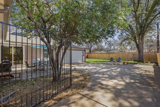 view of patio with a garage, fence, and driveway