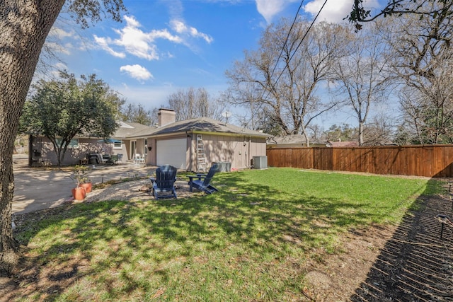 view of yard featuring central air condition unit, an attached garage, and fence