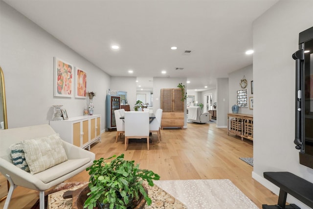 living room with light wood-type flooring, visible vents, baseboards, and recessed lighting