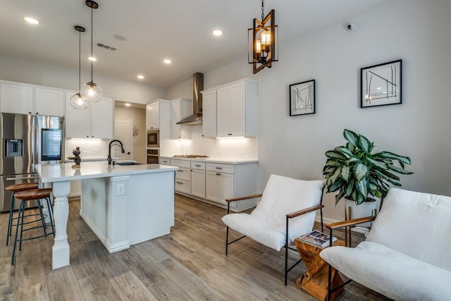 kitchen featuring decorative backsplash, a breakfast bar, stainless steel appliances, wall chimney range hood, and a sink