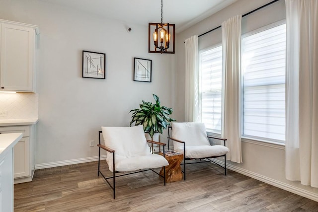 living area featuring baseboards, a notable chandelier, and light wood-style floors