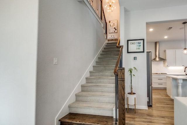 stairway featuring baseboards, visible vents, wood finished floors, a chandelier, and recessed lighting