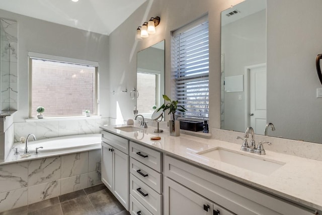 bathroom with visible vents, a sink, a garden tub, and double vanity