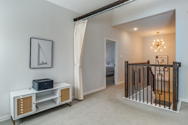 hall with carpet floors, baseboards, a notable chandelier, and an upstairs landing