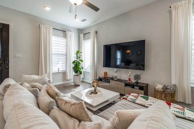 living area featuring visible vents, ceiling fan, baseboards, and wood finished floors