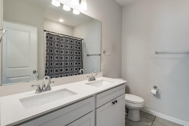 bathroom featuring toilet, double vanity, a sink, and tile patterned floors