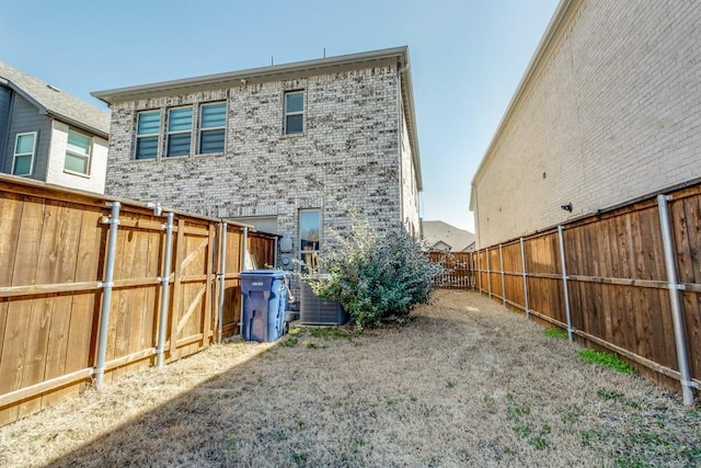 back of property featuring brick siding, fence, and central AC unit