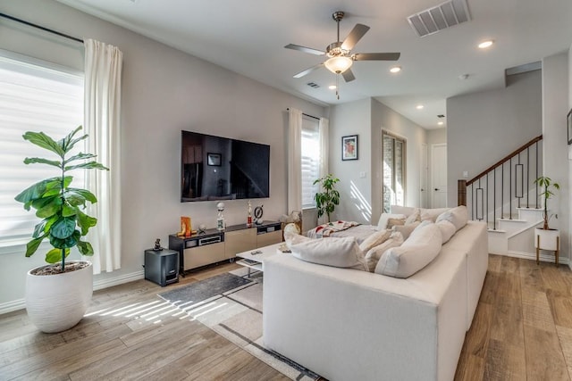 living room featuring recessed lighting, visible vents, light wood-style flooring, ceiling fan, and stairs