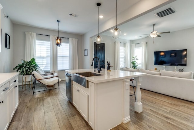 kitchen with open floor plan, wood finished floors, a sink, and visible vents