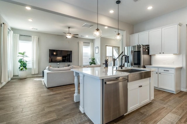 kitchen with visible vents, appliances with stainless steel finishes, open floor plan, wood finished floors, and a sink