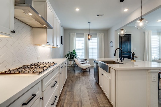 kitchen featuring a sink, visible vents, appliances with stainless steel finishes, wall chimney exhaust hood, and dark wood finished floors