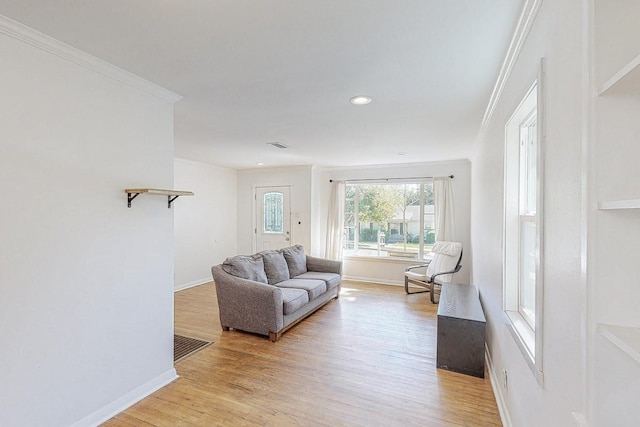 living area with light wood-style flooring, baseboards, and crown molding