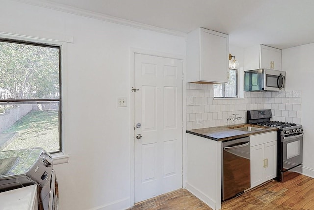 kitchen with appliances with stainless steel finishes, light wood-type flooring, and white cabinets