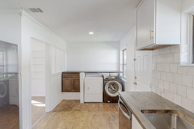 kitchen featuring tasteful backsplash, visible vents, light wood-style flooring, washing machine and clothes dryer, and stainless steel dishwasher