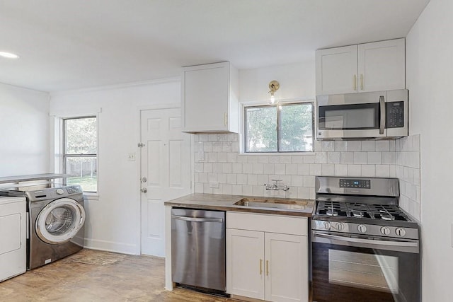 kitchen featuring white cabinetry, washing machine and dryer, appliances with stainless steel finishes, and a sink