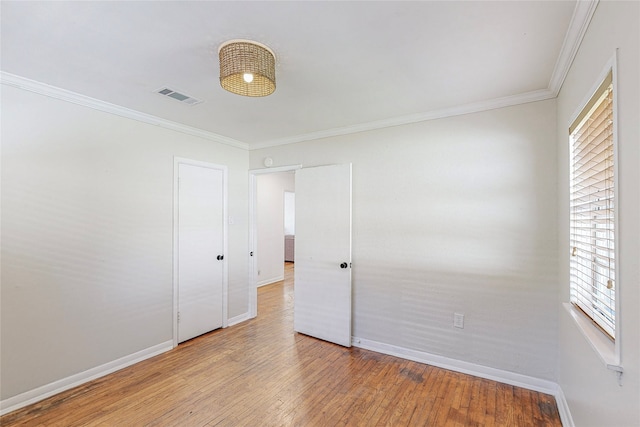 spare room with ornamental molding, hardwood / wood-style flooring, visible vents, and baseboards