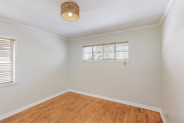 spare room featuring ornamental molding, light wood-type flooring, and baseboards