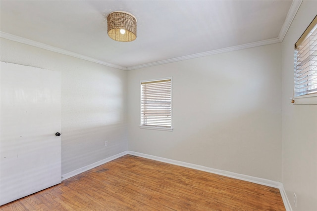 empty room with light wood-style floors, crown molding, and baseboards