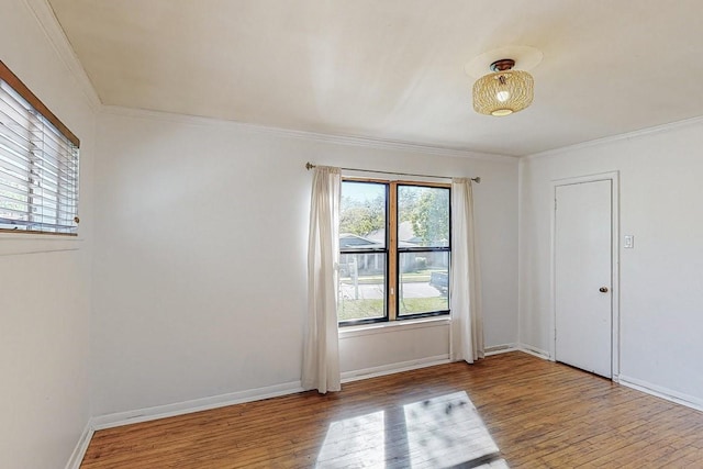 spare room with crown molding, wood finished floors, and baseboards