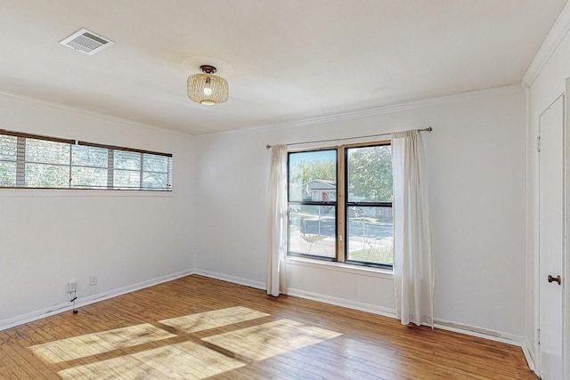 unfurnished room with a wealth of natural light, baseboards, visible vents, and hardwood / wood-style floors