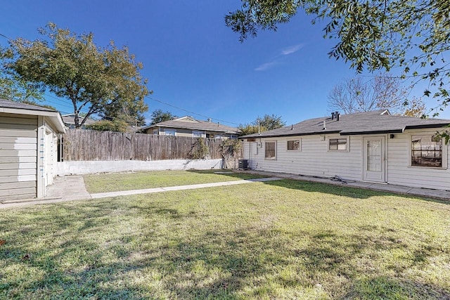 view of yard with central AC and fence