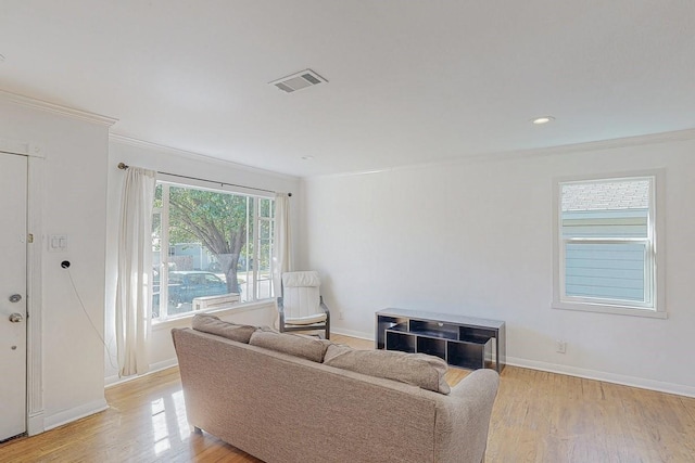 living area featuring baseboards, ornamental molding, visible vents, and light wood-style floors