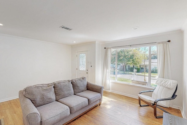 living area featuring light wood finished floors, baseboards, visible vents, crown molding, and recessed lighting