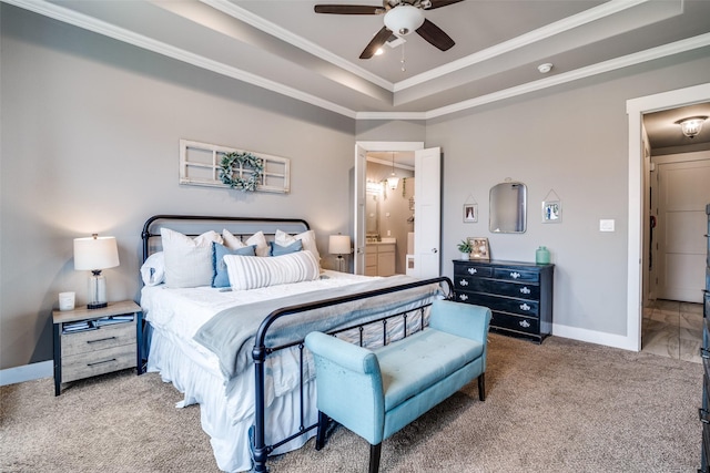 carpeted bedroom with a ceiling fan, baseboards, ornamental molding, a raised ceiling, and ensuite bath